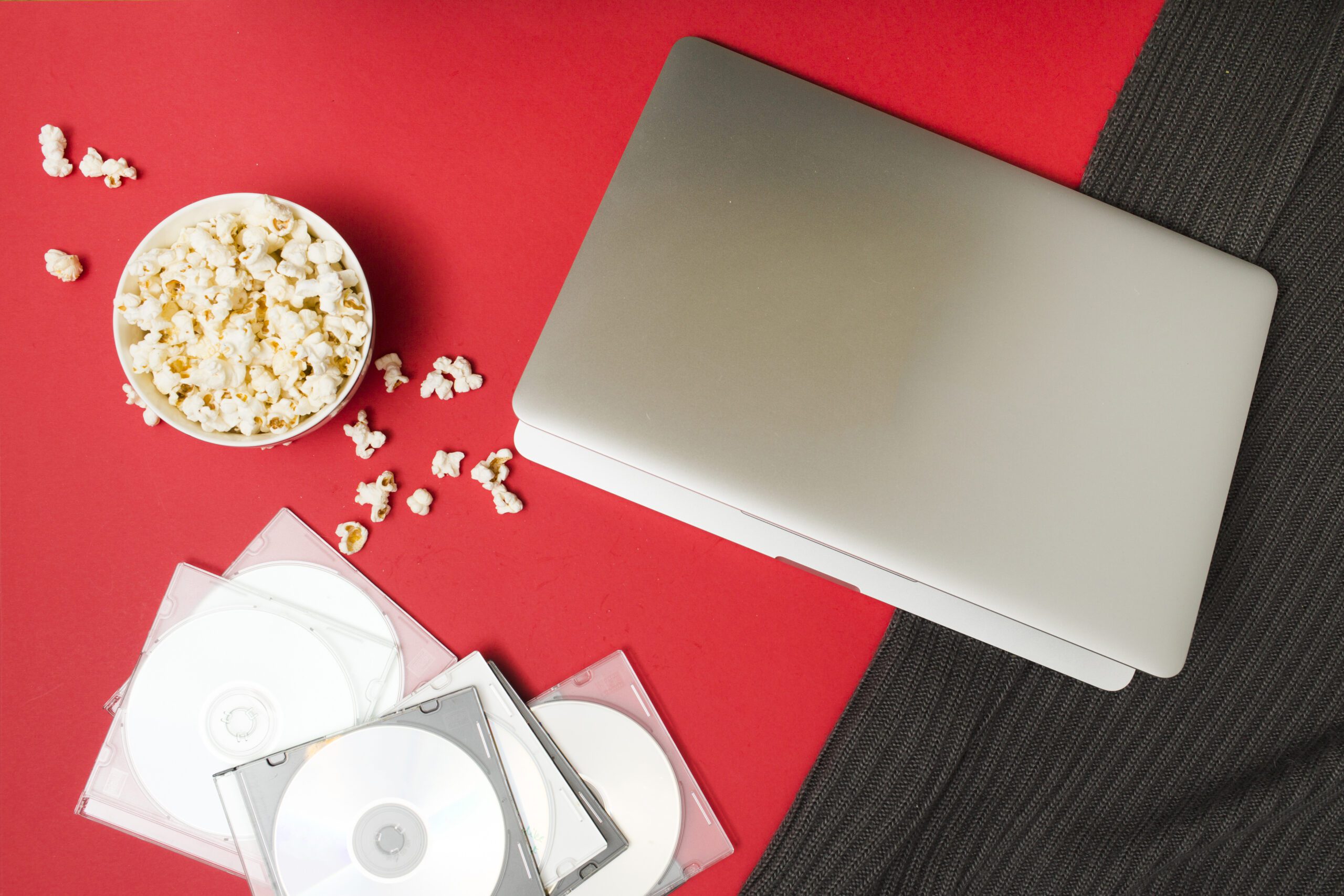 A Laptop, Popcorn and some CDs at the red black table color